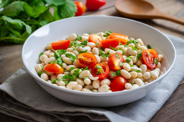 White bean salad with cherry tomatoes and parsley in bowl