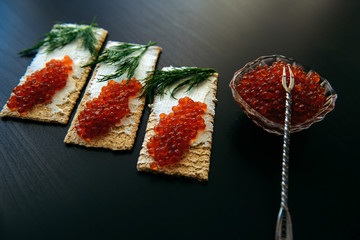 Red caviar on crispy bread with cream cheese and green. Healthy food. Sandwiches with caviar...