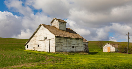 White Barn close-up with green field and white clouds background