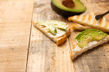 toast with philadelphia cheese, avocado pieces and sesame seeds on wooden background, healthy and healthy food , vegan food, detox