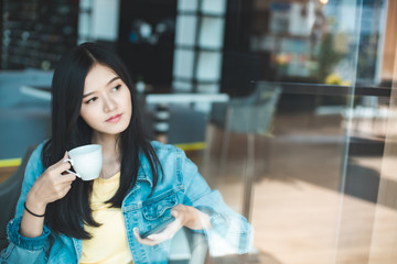 Asian woman in a cafe drinking coffee .Portrait of Asian woman smiling in coffee shop cafe vintage color tone.