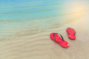 Red flip flops on a sandy ocean beach with wave form