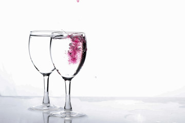 Red food coloring diffuse in water inside wine glass