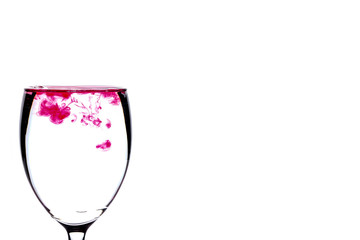 Red food coloring diffuse in water inside wine glass