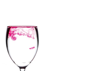 Red food coloring diffuse in water inside wine glass