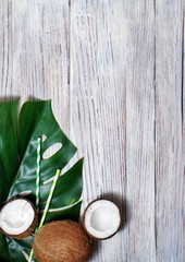 coconuts and tropical leaf of monstera plant with a paper straw cocktail on orange background. Flat layer, top view, copy space. Healthy cooking. Creative concept of healthy eating. horizontal