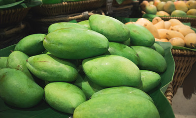 Thai green mango in basket with yellow mango background