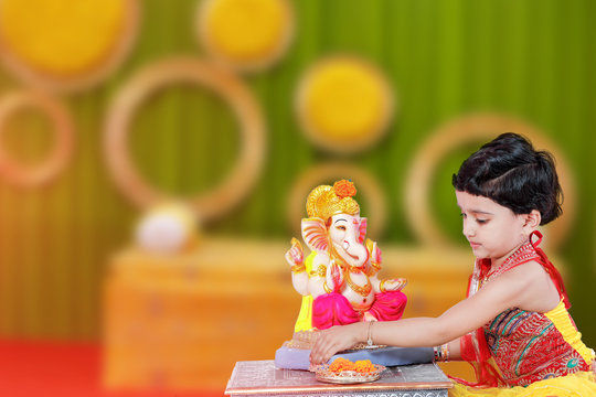 Little Indian child with lord ganesha and praying , Indian ganesh festival