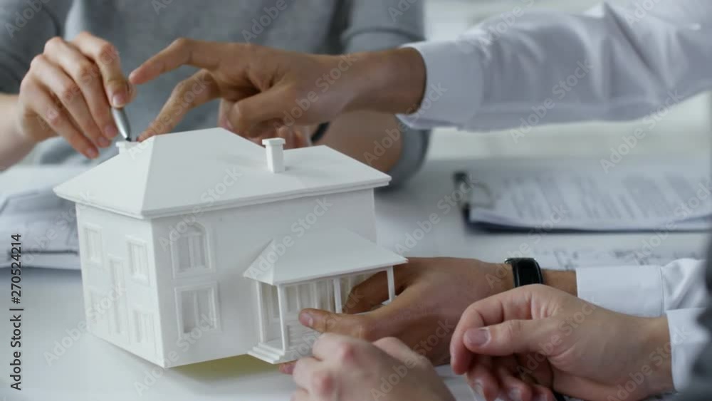 Poster close up shot of hands of unrecognizable architects discussing model of residential building at offi