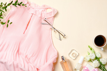 Flat lay feminine accessories, perfume bottle, roses flowers, pink dress, glasses, coffee cup, Top view beauty blogger desk with female stuff, clothes and cosmetic. Fashion blog banner.