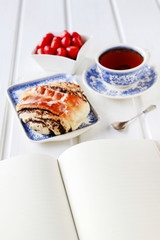 Poppy seed swedish bun and bowl of strawberries.