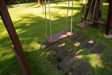 Wooden swing hanging in a beautiful garden near the bungalow. The inner territory of a beautiful hotel on the seafront. Small houses on the resort in Asia.