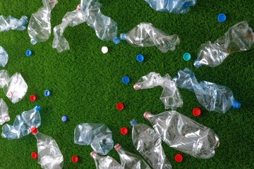 The concept of recycling plastic and environmental protection. Pet preforms for plastic bottles on the green grass. Artificial turf.