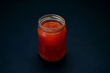 Glass jar of jam on a dark background