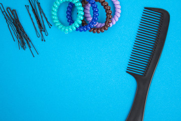 Hairbrush, barrette, hairpins and hair bands lies on blue background. Flat lay.