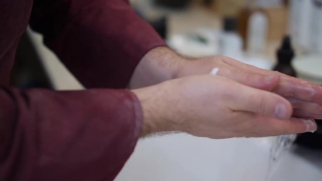 A barber puts cream for the face on his hands