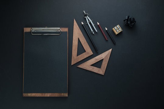 Black on black flat lay with a clipboard, pencils, and rulers. Drawing blueprints header with copy space.