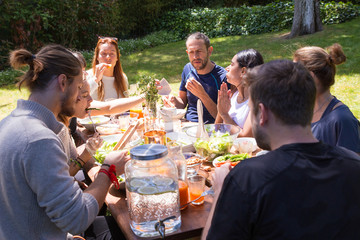 Portrait of serious young people having brunch outdoors. Friends or family eating at table...