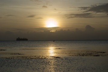 Dull gold colors of sunset with a silhouette of a ship in the distance