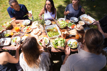 Vegetable and fruit snacks on table and eating people. Young men and women having meal together...