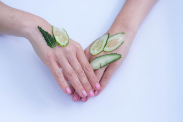 beautiful soft hands of a woman and sliced cucumber skincare