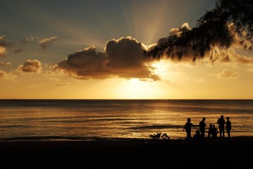 Gorgeous clouds and silhouettes of people on the beach at sunset