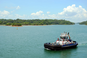 Fototapeta na wymiar Panama Canal tug boats assisting to the transiting cargo ships.