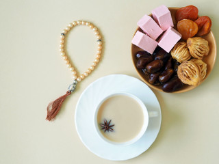 Sweets, dates, dried apricots on a plate, tea on a beige background. The concept of Ramadan, iftar.