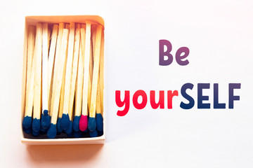 Blue matches and one match of pink color in a box. Difference, self respect and acceptance concept. Motivational phrase on the image. Opposition, unique features and individualism concept.