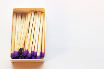 Purple matches and one match of black color in a box. Self respect and yourself acceptance concept. Copyspace on the right side of the image for designers. Uniqueness and individualism concept.