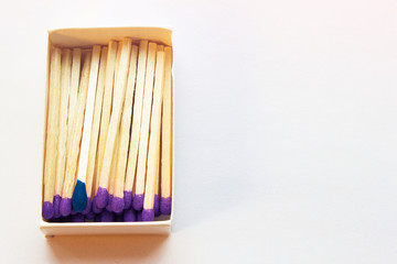 Purple matches and one match of blue color in a box. Self respect and yourself acceptance concept. Copyspace on the right side of the image for designers. Uniqueness and individualism concept.