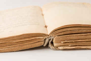 Close-up of open old book with battered binding and yellowed pages. Book spread in poor condition.