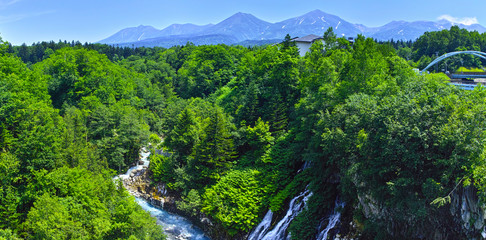 初夏の北海道、美瑛町にある白髭の滝と十勝岳連峰