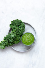 Green smoothies with kale, banana, apple and pear and lemon on marble background with copy space