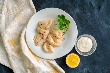top view of cooked dumplings with lemon and creamy sauce and green herbs