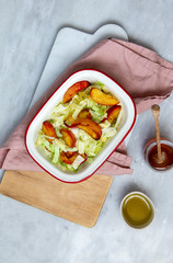 salad with greens and baked peach on marble background with copy space