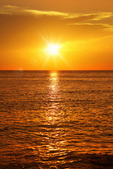 Colorful empty seascape with shiny sea over cloudy sky and sun during sunset in Cozumel, Mexico