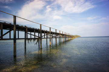 Fototapeta na wymiar Wood bridge stands into the sea with blue sky