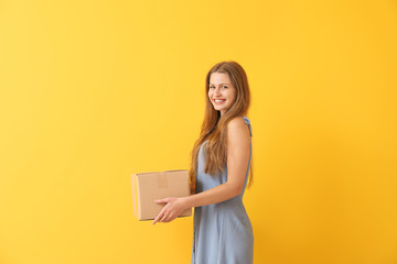 Young woman with cardboard box on color background