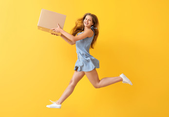 Jumping woman with cardboard box on color background