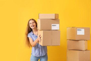 Young woman with cardboard boxes on color background