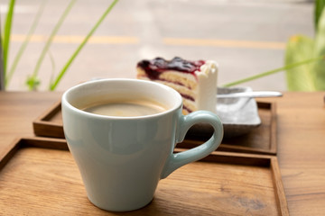 Hot coffee with a blueberry cake in a wooden tray
