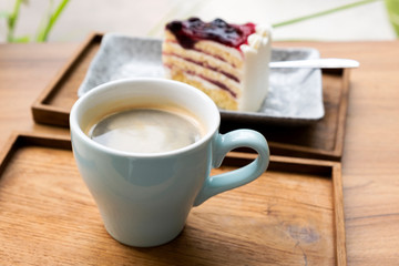 Hot coffee with a blueberry cake in a wooden tray