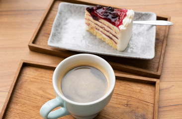 Hot coffee with a blueberry cake in a wooden tray