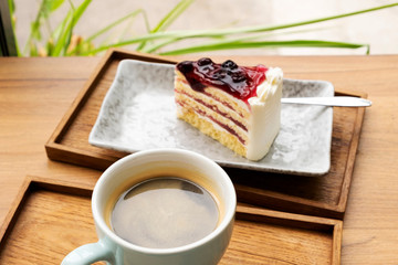 Hot coffee with a blueberry cake in a wooden tray