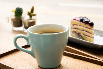 Hot coffee with a blueberry cake in a wooden tray