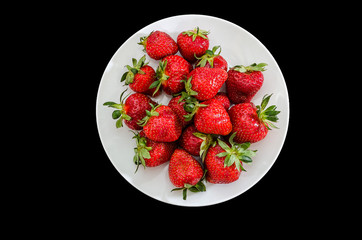 strawberries in a white plate on a black background