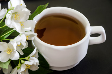 cup of tea with jasmine on a black background, close-up