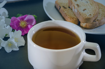 cup of jasmine tea with rusks on a black background, close-up