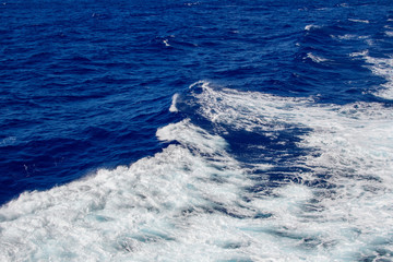 Naklejka na ściany i meble Blue ocean wave with white sea foam on top.